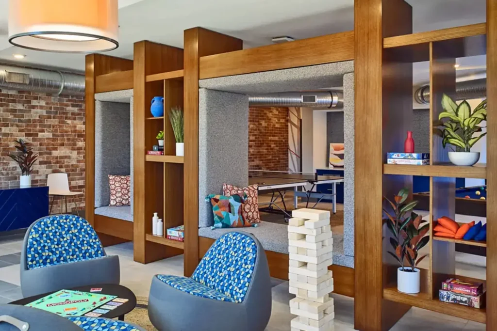 Shared resident lounge with study pods and game table at 320 West Mag, Auburn student housing.